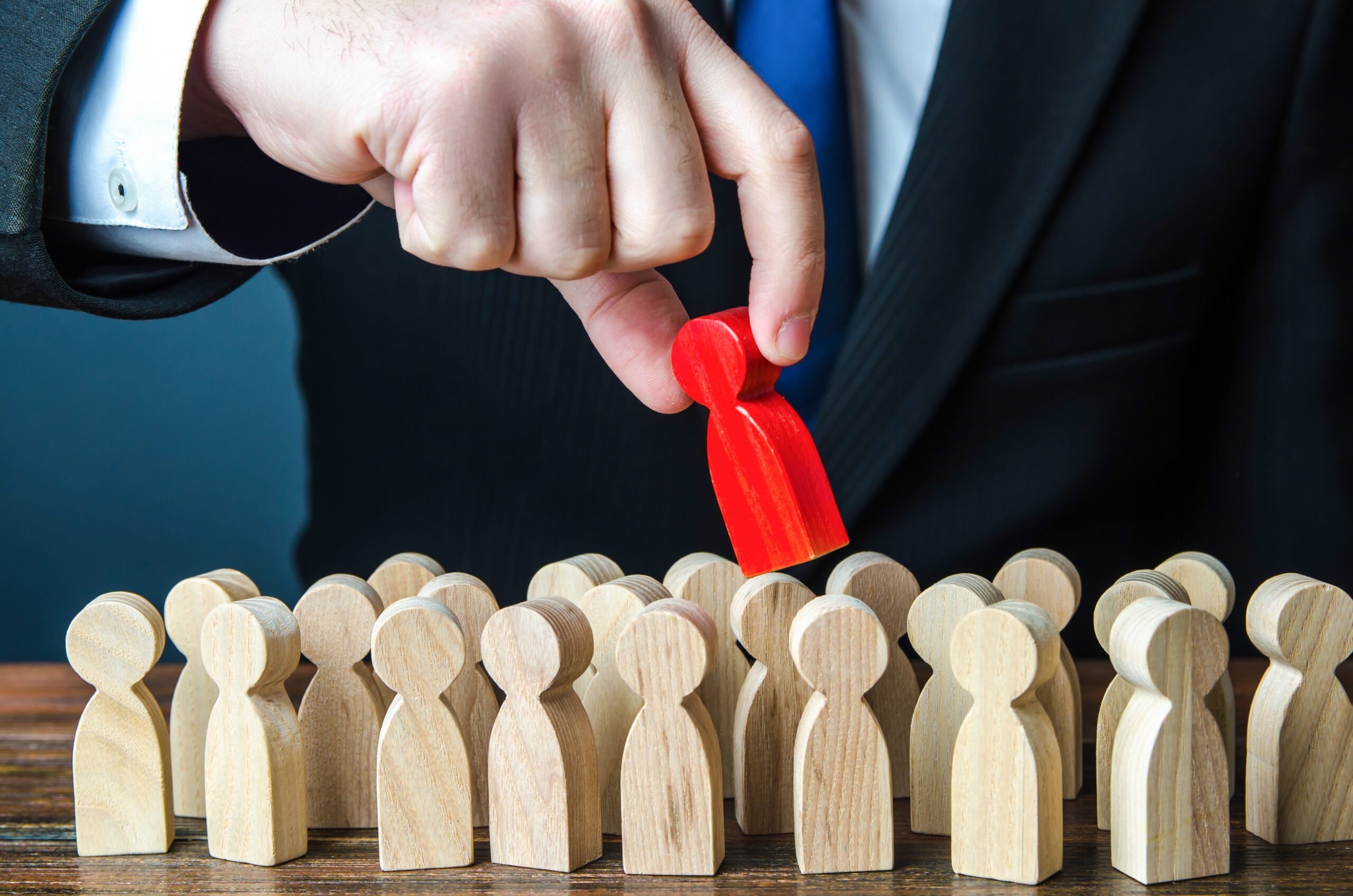 Man in suit removing a red colored piece from a bunch of un-colored pieces, representing the concept of employment discrimination